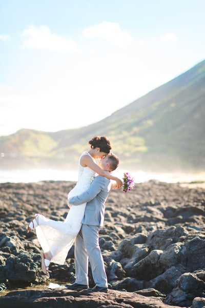Newlyweds kissing on lava rocks