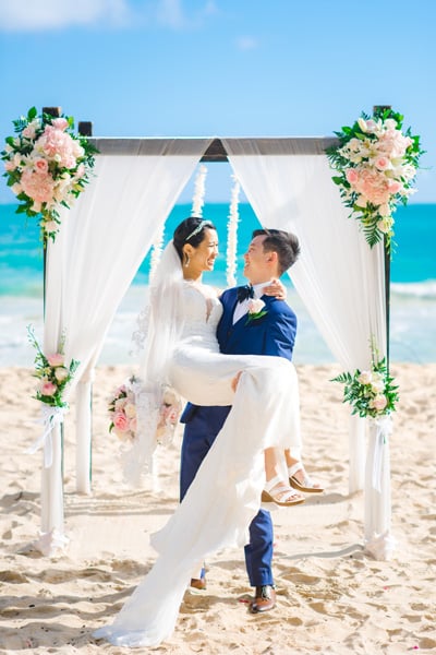A groom lifting his wife at a Hawaii beach elopement