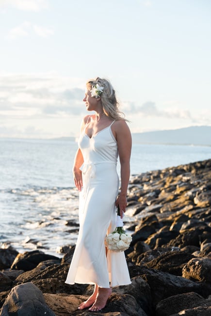 A bride in Hawaii standing on lava rocks