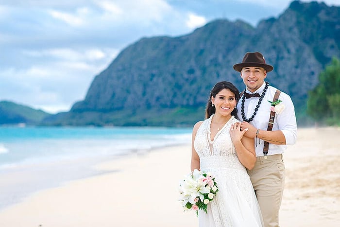 Newlyweds posing for a photo on the beach in Hawaii
