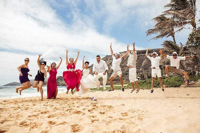 A wedding party celebrating the sun coming out for their beach wedding