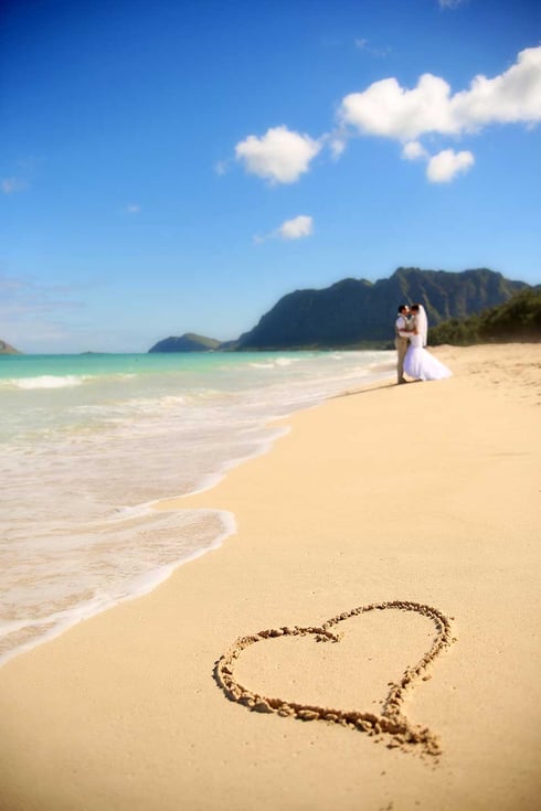 Beach wedding in Hawaii sand heard with couple in the background