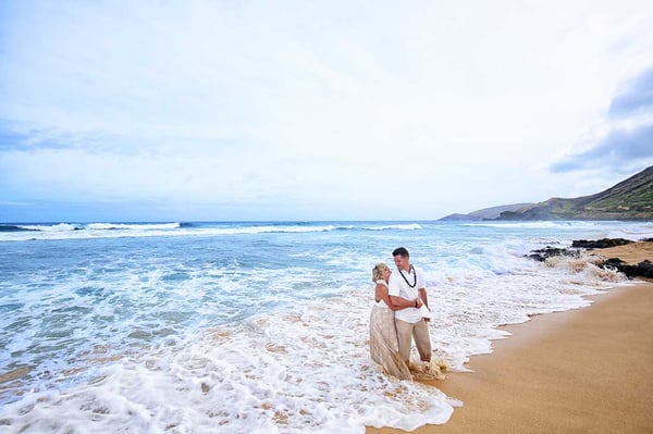 Newlyweds play in the water after their beach wedding