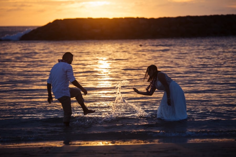 Newlyweds splash in the ocean after their ceremony
