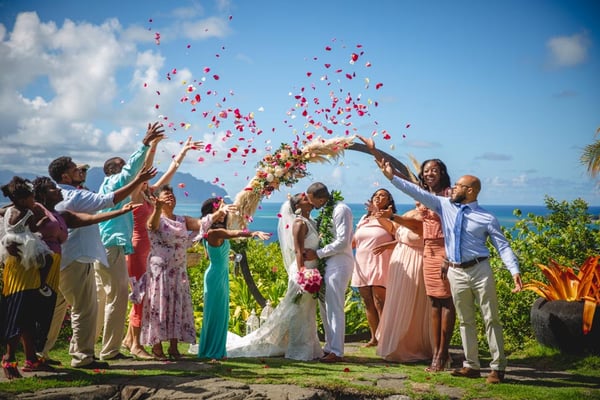 A flower shower for newlyweds in front of a wedding arbor in Hawaii