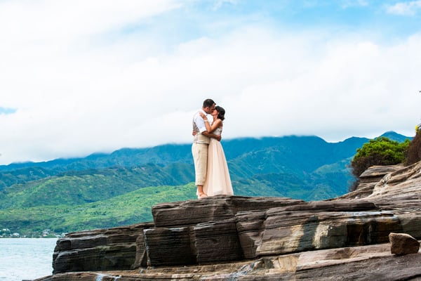 Newlyweds kissing on lava rocks in Hawaii