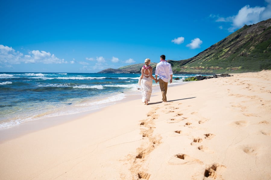 Elopement couple walking on the beach in Hawaii and leaving footprints