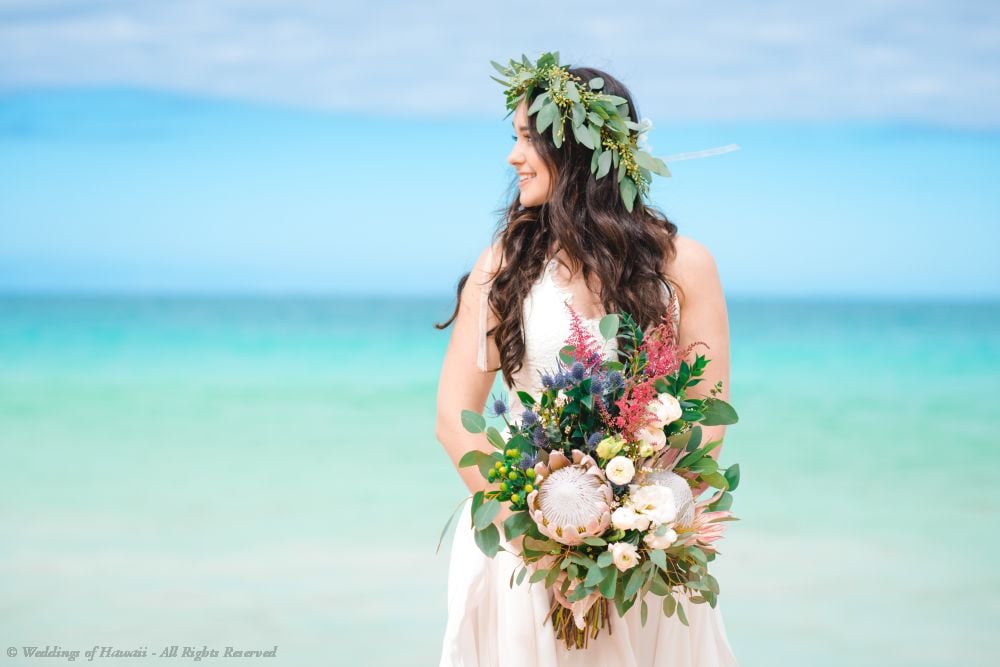 A bride in Hawaii wearing a haku lei and holding a bridal bouquet