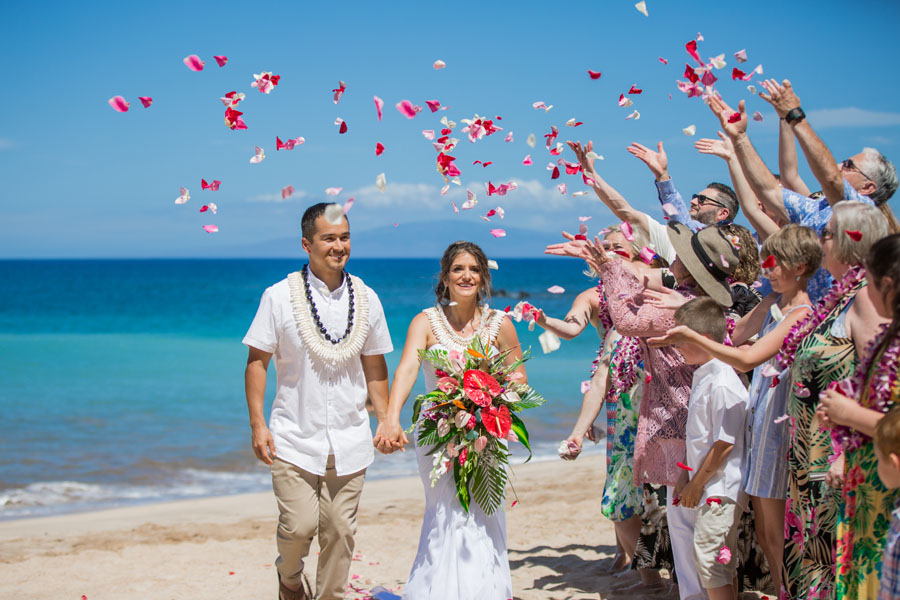 Small wedding group tossing flowers on a Maui beach